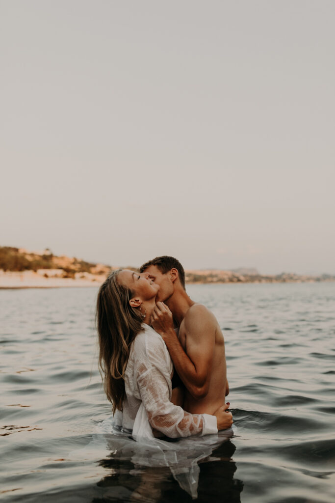 Photo de couple à la mer au lever du soleil